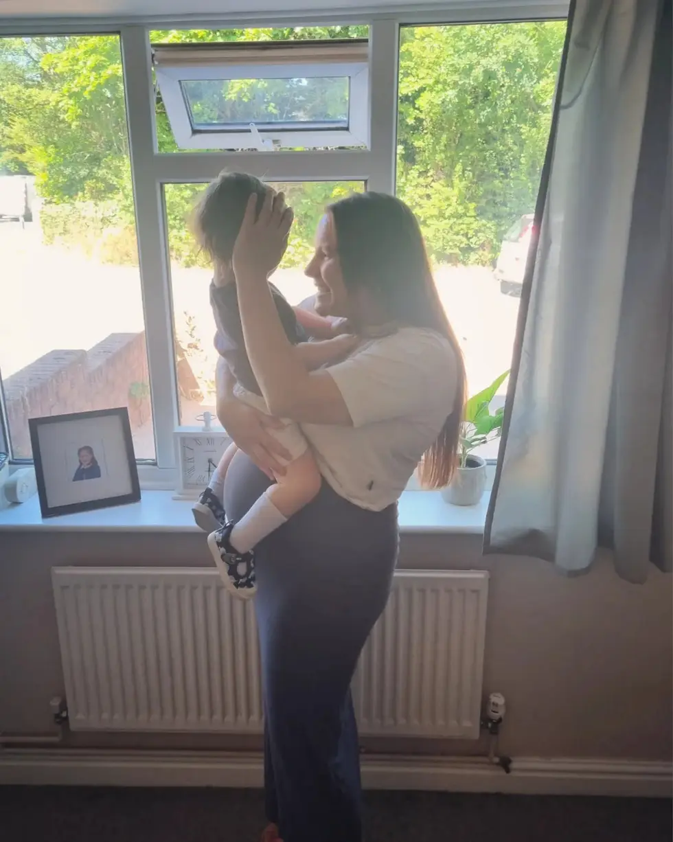 Donna at home lifting her toddler up by the window