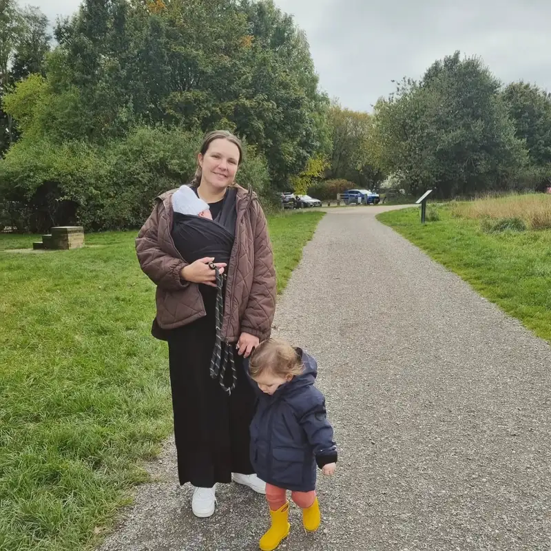 Donna out walking with her newborn in a sling and her toddler