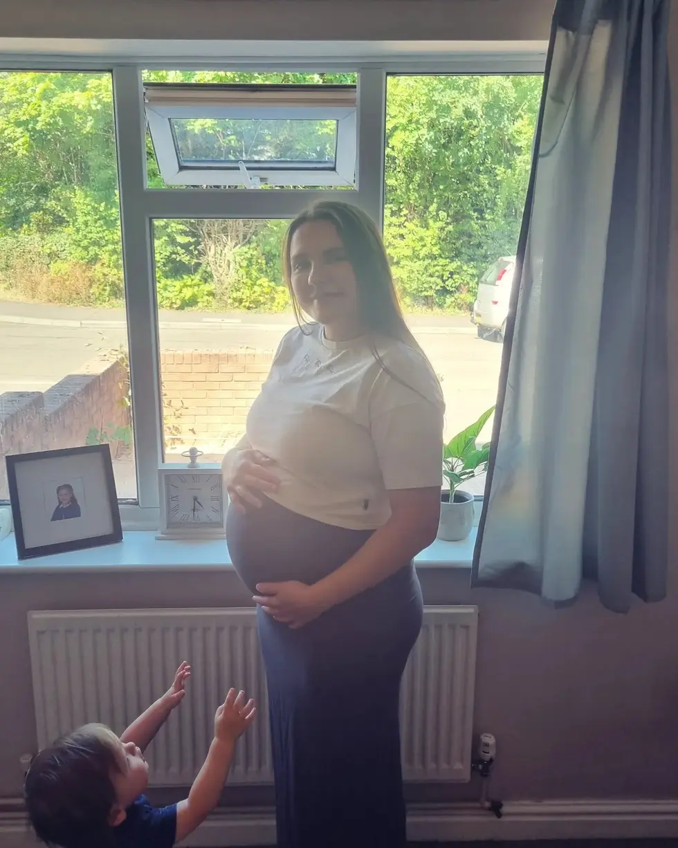 Donna at home during her second pregnancy, with her eldest son reaching up to her