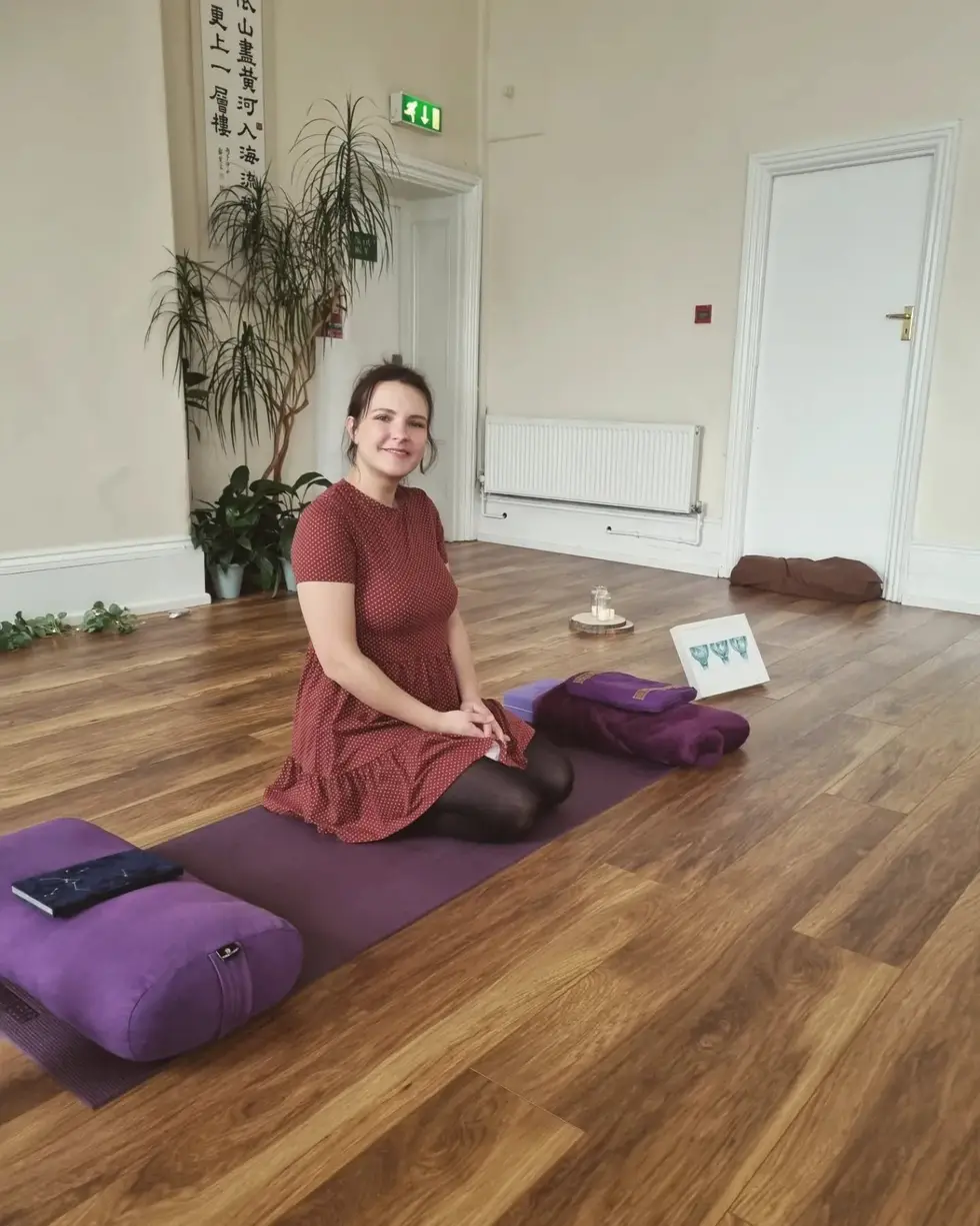 Donna sitting on a mat in a calm studio space set up for a class